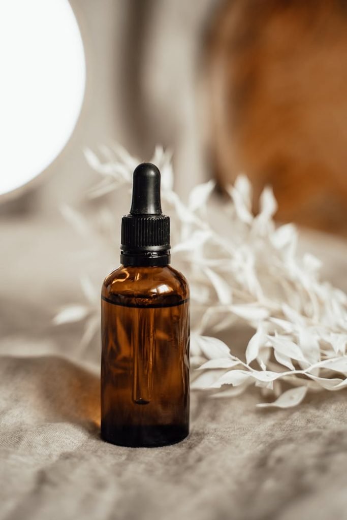 dropper-glass-bottle-on-linen-7795850 Elegant amber glass dropper bottle with organic oil and white botanicals on a cozy linen background.
