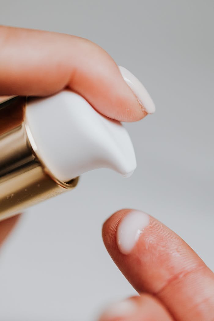 Detailed close-up of a womans hand applying facial cream, highlighting skincare and beauty routine.